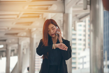 Time out concept. Urgent work, business woman seeing wrist watch and using mobile phone before meeting. Smart woman check the schedule before going to the office. Time out for appointment meeting.