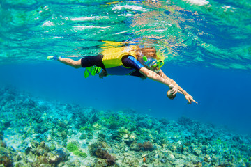Happy family - mother, kid in snorkeling mask dive underwater, explore tropical fishes in coral...