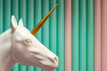 white plastic unicorn on green background front side © Emilia