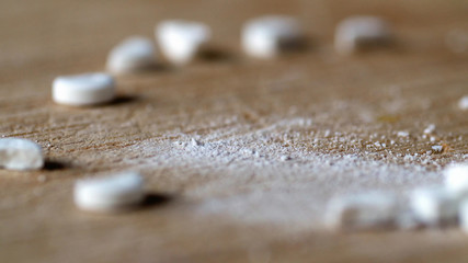 closeup view cutting white round pill by knife on wooden board