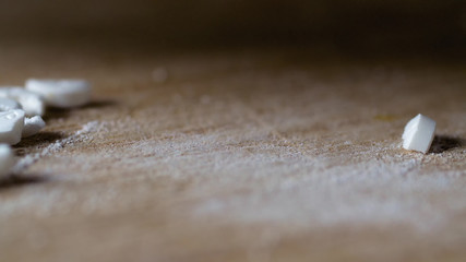 closeup view cutting white round pill by knife on wooden board