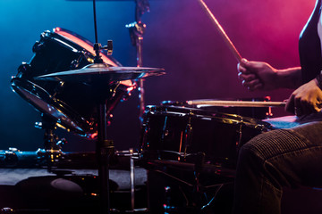 cropped shot of male musician performing on drums during rock concert on stage