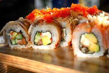 Traditional seafood in Asia or Japan. Maki sushi rolls sprinkled with flying fish roe lie on a wooden table.