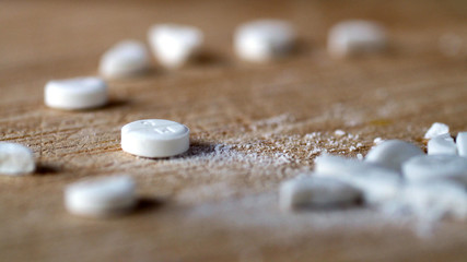 closeup view cutting white round pill by knife on wooden board