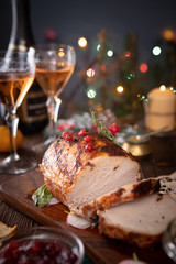 Sliced pork lies on a festive table with New Year's décor and Christmas lights in the background