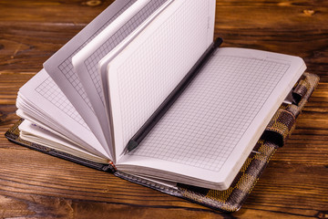 Opened notepad and pencil on wooden table