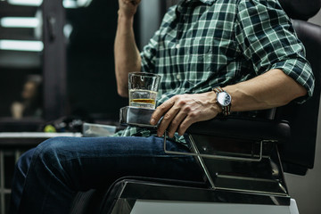 Close up of glass of whiskey standing in the barber chair elbow