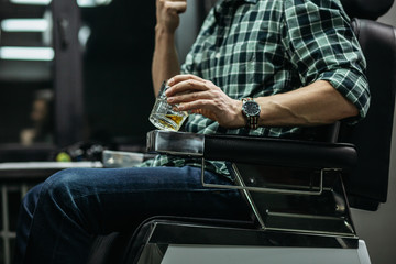 Fototapeta na wymiar Man in checkered shirt sitting and holding glass of whiskey