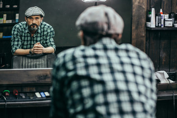 Waist up of middle aged bearded man standing in barbershop