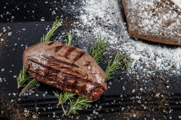Top view of grilled filet mignon beef steaks on a black wooden surface