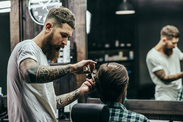 Calm careful barber combing hair of his client