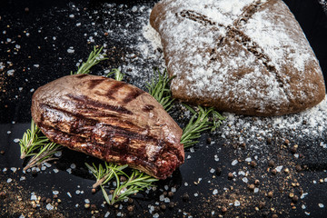 Top view of grilled filet mignon beef steaks on a black wooden surface