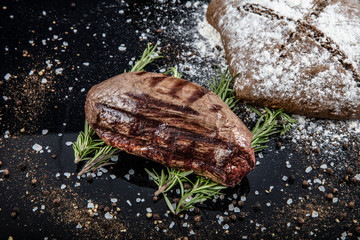 Top view of grilled filet mignon beef steaks on a black wooden surface