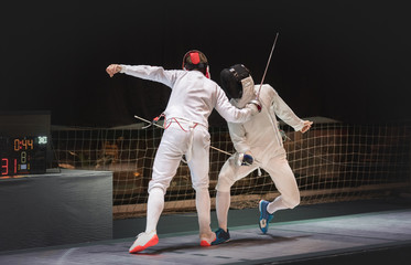 Two man fencing athlete fight on professional sports arena