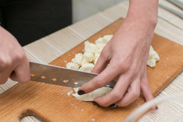 Woman slices cheese on a cutting board.
