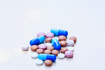 Medications of various colors on a light background.