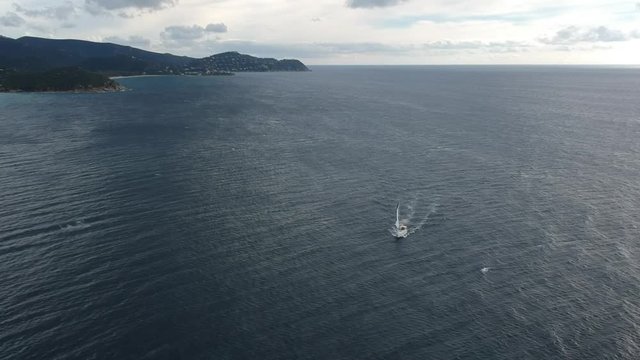 High Above a Sailboat Sailing to Shore in a Heavy Wind to Seek Safety in a Natural Harbor in Sardinia Italy