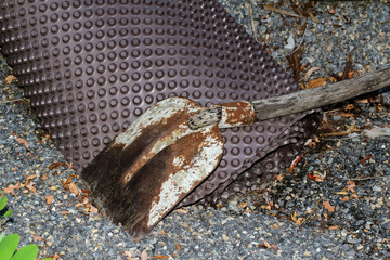 Rostige Schaufel und braune Noppenmatte