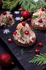 Canape shaped as a Christmas tree with pate garnished with pomegranate and dill surrounded by...