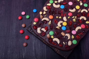 Dark chocolate bark with cashew and pistachio nuts, multicoloured sweets, dried cranberries and cherries