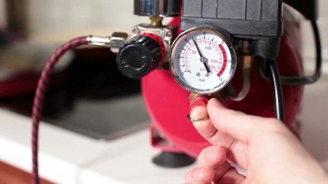 Bleeding of air from the receiver of the compressor, close up view at hand and manometer