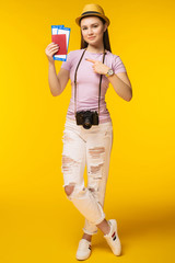 Traveler tourist woman in summer casual clothes, hat showing thumb up isolated on yellow background.