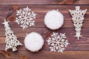 Christmas decoration with snowflakes, balls and fir trees on wooden background. Top view
