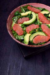 Salad with kale, avocado and grapefruit against the dark background