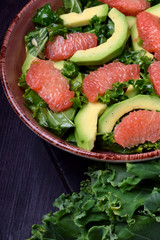 Salad with kale, avocado and grapefruit against the dark background