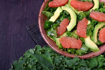 Salad with kale, avocado and grapefruit against the dark background