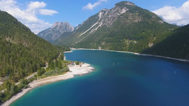 Aerial view of Lake Predil with turquoise water and mountains in background near Tarvisio in European Alps, Italy
