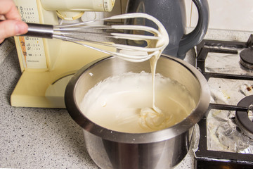 Iron bowl with dough in which the whisk mix the ingredients