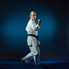 On the blue tatami man performs formal karate exercises © andreyfire