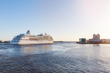 White cruise ship passes barrage gates Gulf of Finland in St. Petersburg, sunny weather and calm sea.