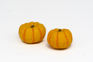 Two isolated small yellow pumpkin in the foreground with a wide and clean white background