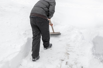 A man cleans snow shovel near the house