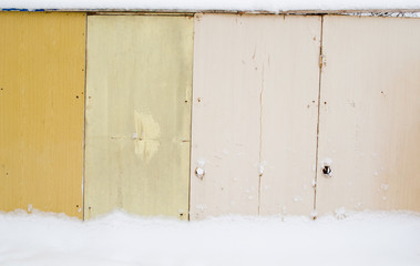 Wooden fence. Old boards. Snow on the fence. Scratched paint.
