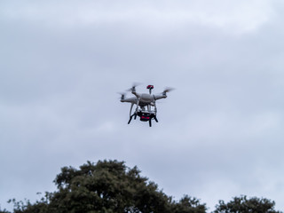 A drone in motion flying in forest in the cloudy sky and trees near