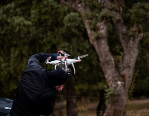A drone pilot configuring his drone in the forest before flying