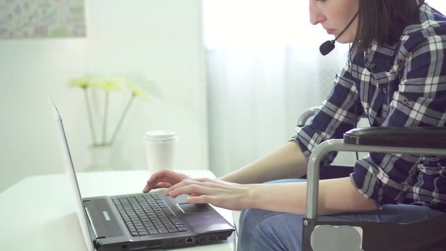 portrait young woman disabled, wheelchair, remote work at home, computer headset