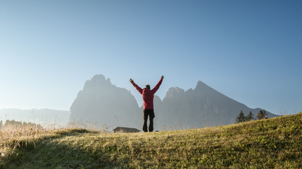 A man in the mountains with raised hands in a gesture of joy. Tourist in the mountains