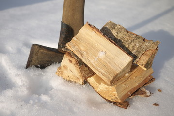 Axe and firewood for stove on snow.