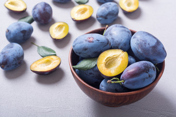 Fresh plums in bowl on wooden table