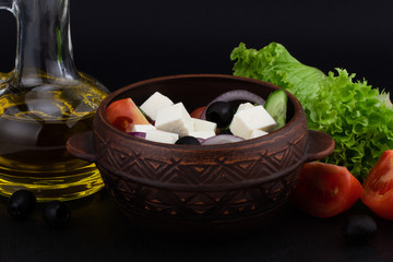 Greek salad with fresh vegetables, feta cheese and black olives on a dark background