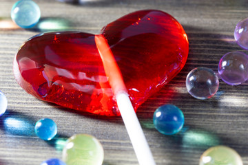Red lollipop in shape of heart and colorful sweet candies, love treat for Valentine’s day 14 February, selective focus