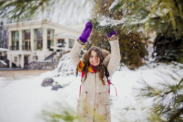 Fototapeta na wymiar Beautiful young Caucasian woman joy happiness smile play with snow near a coniferous tree in a snowy park