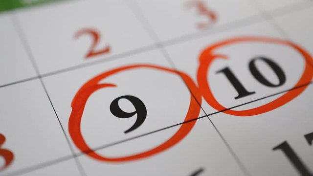 Signing a day on a calendar by red pen nine and ten organizer number