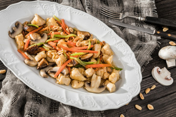 Christmas meat dishes with grilled vegetables, nuts, mushrooms on plate with fork over wooden rustic background. Top view