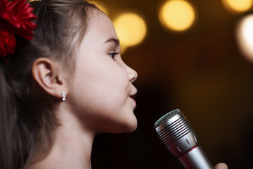 The girl with the microphone. A small child sings karaoke closeup