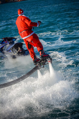 Vertical View of Santa Claus Flying on Flyboard on Blur Background